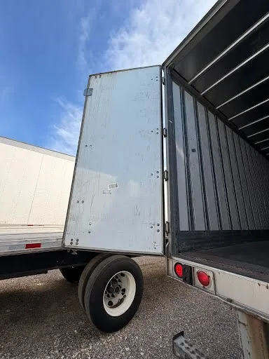 Rear door fully open showing swing door hinges and dual rear wheels in good condition